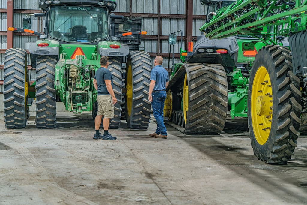 Two men looking over the John Deere fleet