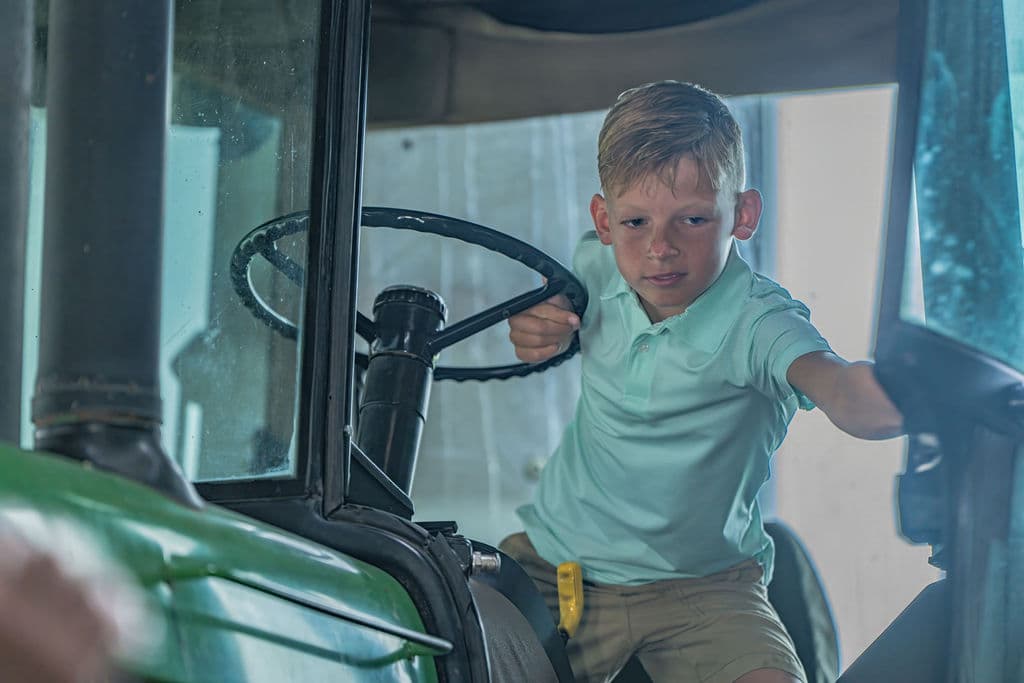 A young hand at the wheel of the old John Deere