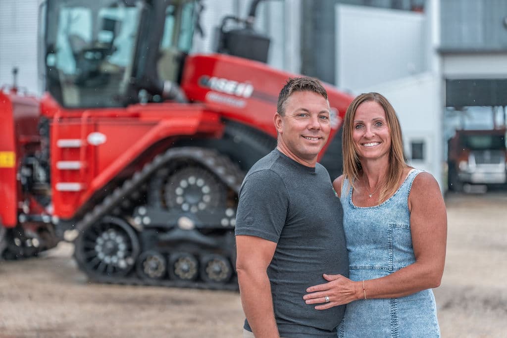 A couple standing in front of the red combine