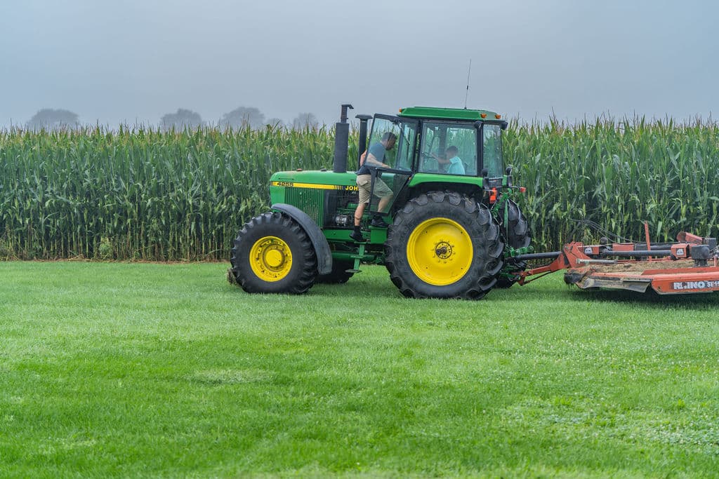 The vintage John Deere hitched to the Rhino mower