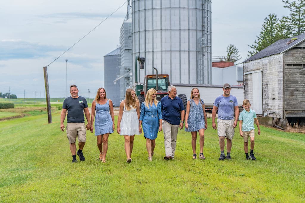 The seventh-generation Riechers family walking the yard, grain bins behind