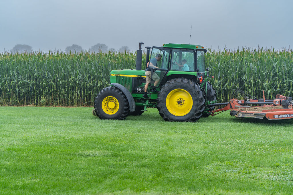The vintage John Deere hitched to the Rhino mower
